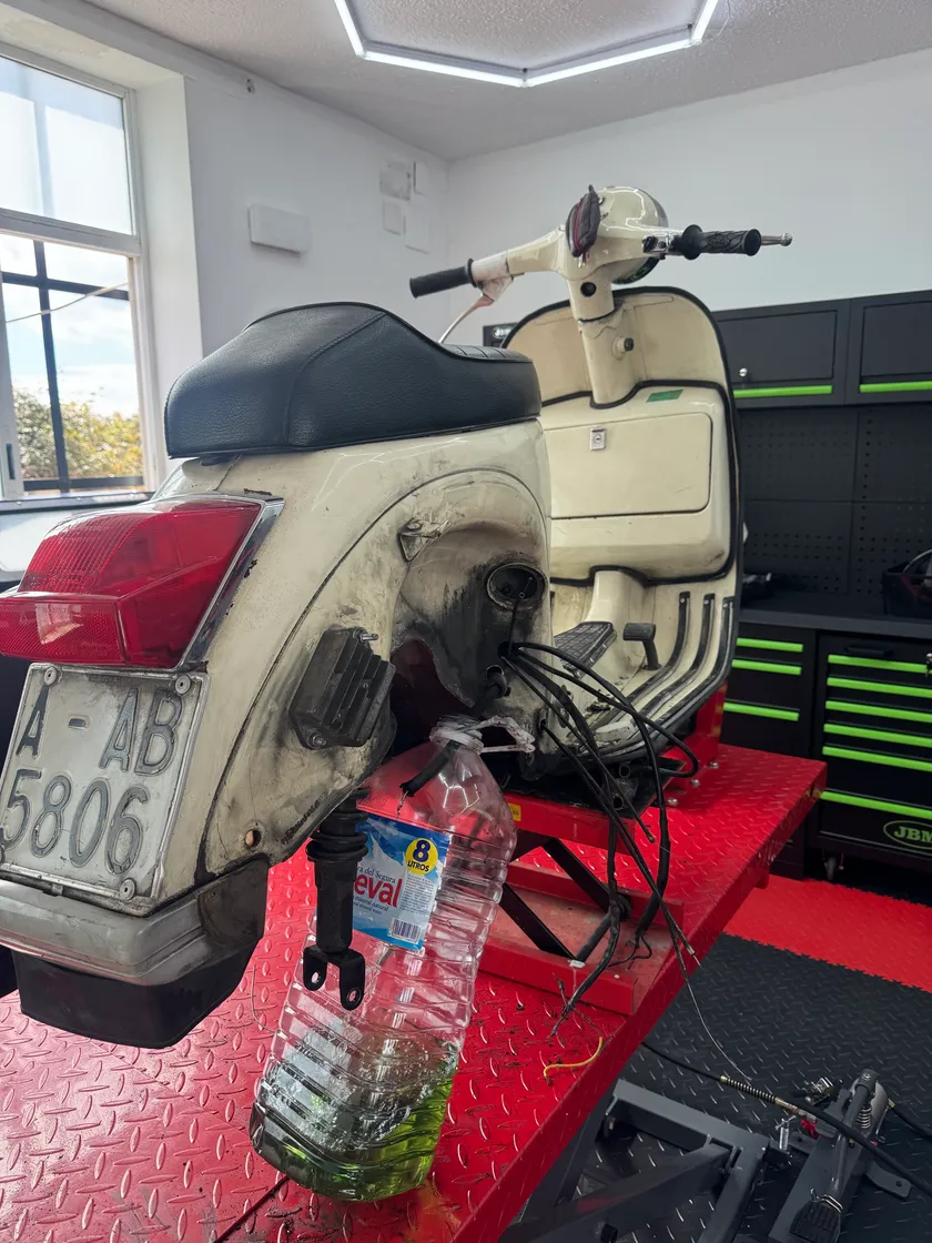 La moto antes de restaurar, subida al elevador del taller, con la pintura sucia y la carrocería desconchada.