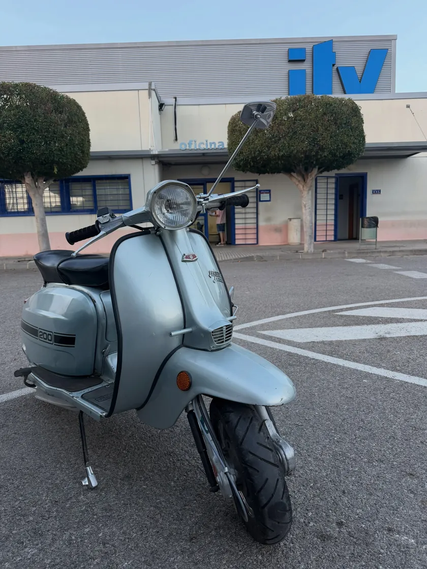 La misma moto restaurada y repintada en gris claro, aparcada a la puerta de la ITV.